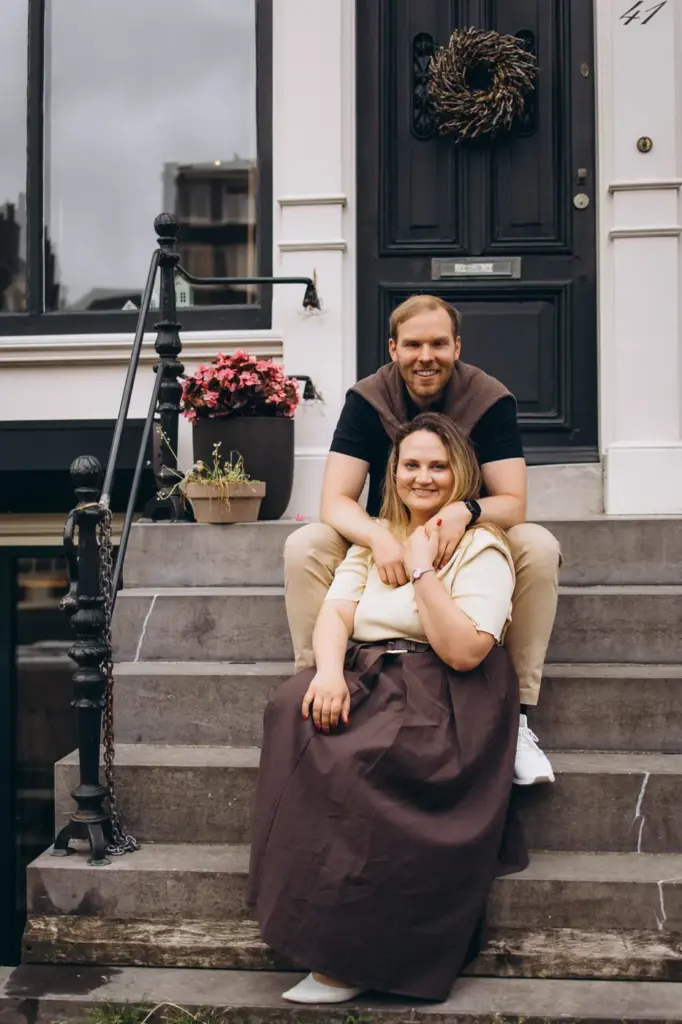 Couple sitting on the steps of a canal house with a wreath on the door