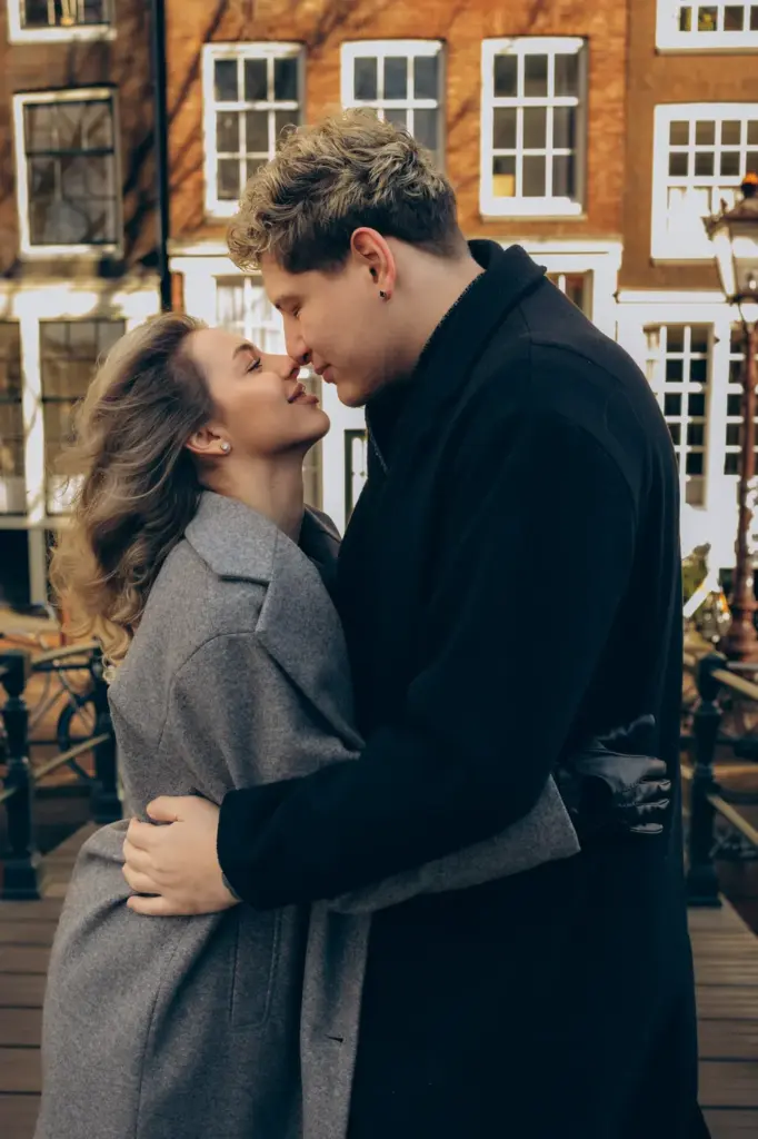 Couple embracing on a canal bridge in front of brick canal houses