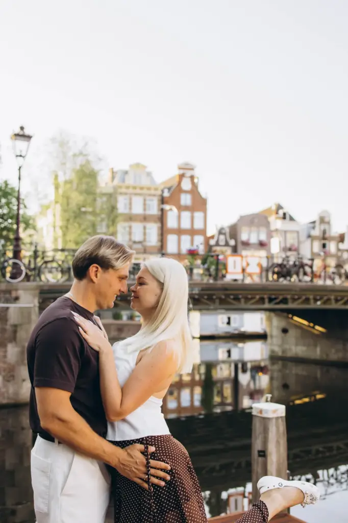 Couple on a canal pontoon with a bridge and canal houses behind them