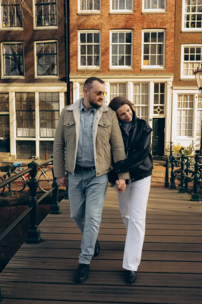 Couple walking hand in hand on a wooden canal bridge in Amsterdam