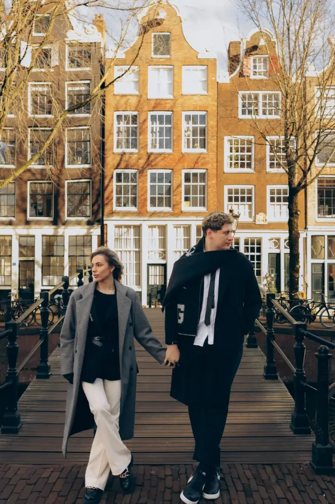 Couple walking hand in hand on a wooden canal bridge