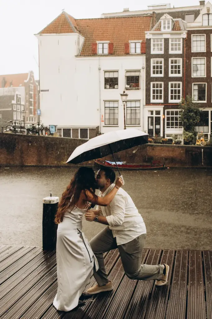 Couple hugging under an umbrella on a canal pontoon right after the proposal