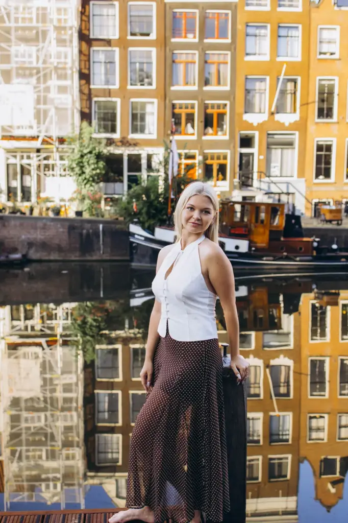 Woman on a canal pontoon with ochre canal houses reflected behind her, Amsterdam