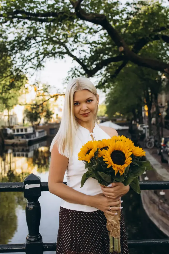 Woman holding sunflowers by a canal railing in Amsterdam
